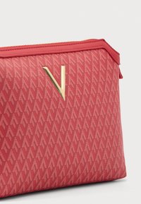Borsetta rossa con cerniera e motivo a V ripetuto. Dettagli in oro sul davanti. Tessuto strutturato con bordi lisci e forma rettangolare.