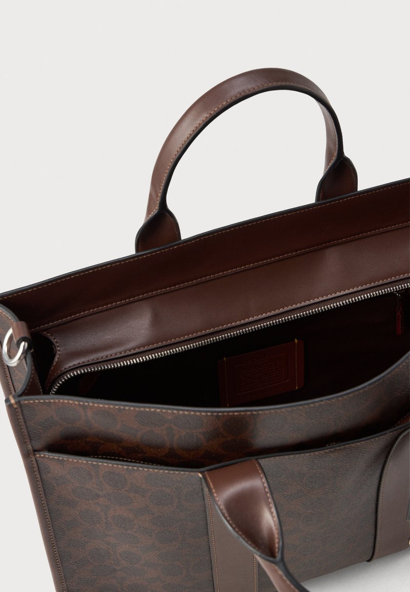 Borsa in pelle marrone con un motivo testurizzato, doppio manico e tasca interna con zip. L'interno è di un semplice marrone con una finitura morbida.