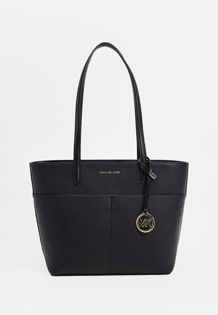Zwarte leren Michael Kors tote bag met twee schouderbanden en een gouden cirkelvormige MK-logo hanger aan de voorkant.