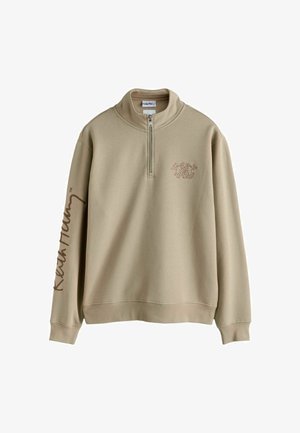 Sudadera beige con cuello alto y media cremallera. Presenta un logo sutil impreso en el pecho y texto a lo largo de la manga izquierda. Tejido de mezcla de algodón.