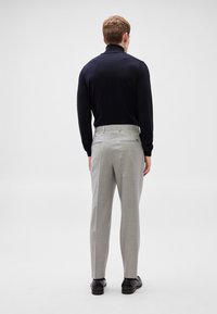 Camisola de gola alta azul-marinho combinada com calças cinza claro, apresentando uma textura suave e corte ajustado, completada com sapatos pretos.