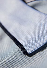 Texturerad tyg i ljusblått med en marinblå kant, som har ett nätmönster och en slät yta, vilket framhäver en lagerdesign.