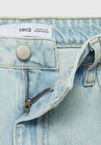 Lichtblauwe denim jeans met een zilveren knop en een metalen rits. Heeft contrasterend stiksels en een waslabel aan de binnenkant van de tailleband.