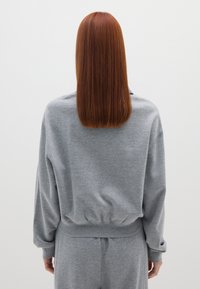 Sudadera gris con un corte relajado, dobladillo de canalé y mangas largas. La textura parece suave; diseño liso sin patrones ni acentos visibles.