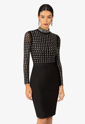 Schwarzes Kleid mit einer figurschmeichelnden Silhouette, langen transparenten Ärmeln und hohem Kragen, verziert mit silbernen quadratischen Nieten und einem glatten Rock.