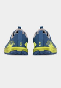 Μπλε και κίτρινα παπούτσια για τρέξιμο σε μονοπάτια, φαίνονται από πίσω, με λογότυπο GTR και ανθεκτικές σόλες σε λευκό φόντο.