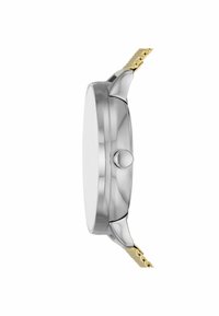 Caja de reloj de acero inoxidable plateado con forma redonda y suave, que presenta una correa en tono dorado y una corona prominente en el lateral.