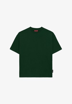 T-shirt en coton vert foncé avec un col rond, des manches courtes, une coupe décontractée et une petite étiquette noir en bas à gauche.