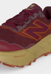 Μπορντό και πορτοκαλί αθλητικό παπούτσι New Balance Fresh Foam με υφή στη σόλα και λεπτομερή κορδόνια σε λευκό φόντο.