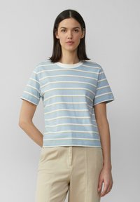 Lichtblauw gestreept T-shirt met witte en crèmekleurige horizontale strepen, ronde halslijn, korte mouwen en een casual pasvorm. G gedragen met beige broeken.