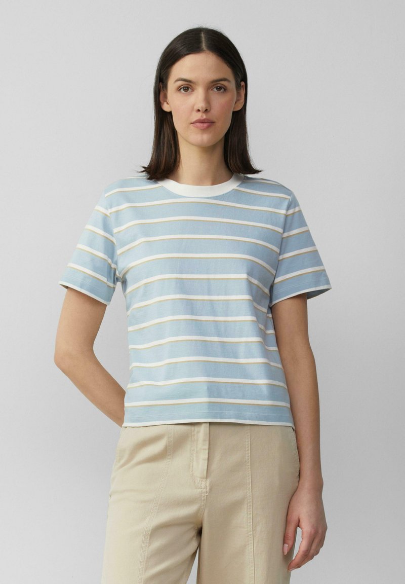 Lichtblauw gestreept T-shirt met witte en crèmekleurige horizontale strepen, ronde halslijn, korte mouwen en een casual pasvorm. G gedragen met beige broeken.