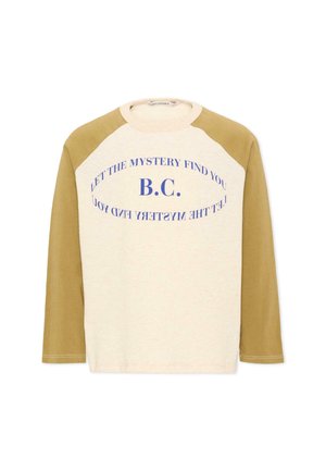 Bluza raglan z długim rękawem z beżowym tułowiem i musztardowymi rękawami, z nadrukiem niebieskiego tekstu "B.C." i "LET THE MYSTERY FIND YOU" w zakrzywionych liniach.