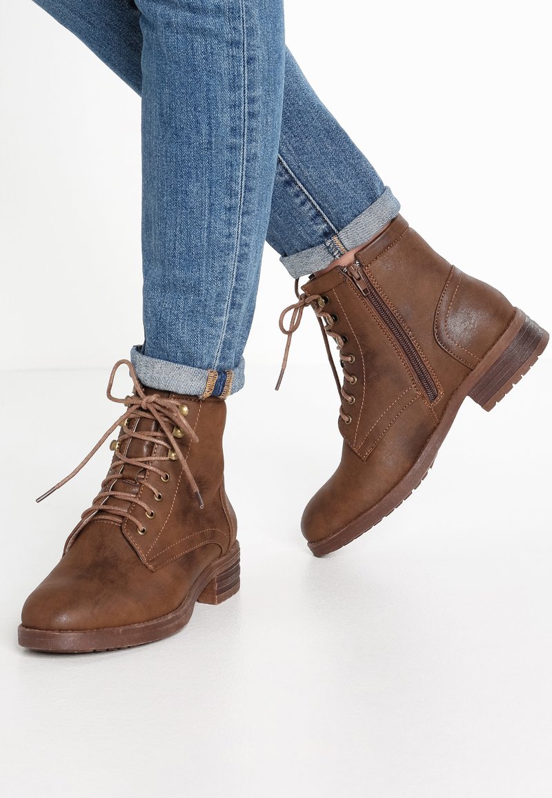 Brown lace-up ankle boots with a shiny finish, featuring six metal eyelets, a side zipper, and a low stacked heel.