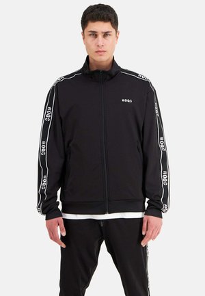 Black athletic zip-up jacket with white logo and side stripes. Features long sleeves, a high collar, and a smooth texture.