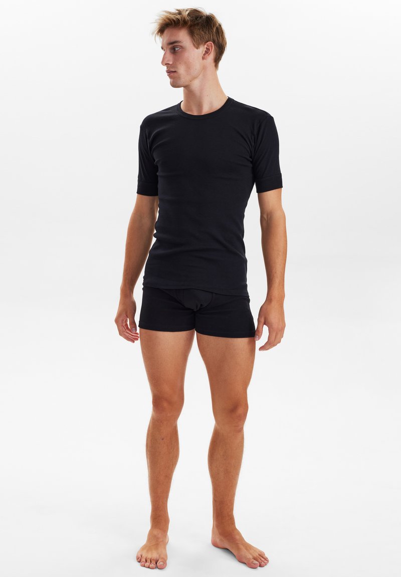 Sort kortærmet t-shirt parret med sorte tætsiddende trusser, glat tekstur, enkelt design og standard rund hals i en enkel stil.