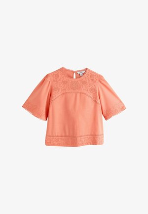 Koralowa bluzka z krótkim rękawem z haftowanymi kwiatowymi i abstrakcyjnymi wzorami na klatce piersiowej, rękawach i dolnym brzegu, z okrągłym dekoltem i pętelką na guziki z tyłu.