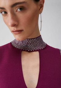 Robe ajustée violette avec un col texturé orné de bijoux, une découpe en forme de goutte d'eau et des accents argentés. Tissu lisse et design moderne.