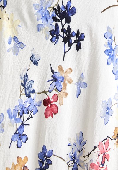 Floral fabric featuring blue, yellow, red, and brown flowers on a white background with a textured, slightly wrinkled surface.
