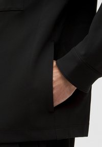 Must tume tekstuuriga särk peidetud taskuga, lõigatud külgõmblustega ja käistelt voltidega. Sile kangas kergelt särava pinnaga, modernne disain.