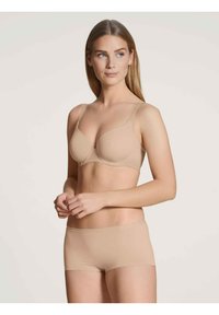 Beige naadloze beha met verstelbare banden en ronde cups, gecombineerd met beige boyshorts. Gladde textuur, eenvoudig ontwerp zonder zichtbare bevestigingsmiddelen.