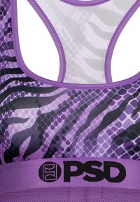 Lilla sportsbh med nettdesign som har zebra- og slange mønstre. Justerbare stropper og et bredt svart merke-bånd i bunnen.