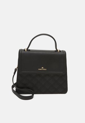 Black quilted leather handbag with a top handle and detachable shoulder strap. Gold logo detail on front. Rectangular shape with structured design.