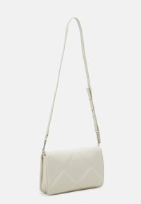 Biela crossbody taška vyrobená z syntetického materiálu, s prešívaným dizajnom a diamantovými vzormi, nastaviteľným popruhom a striebornými akcentmi.