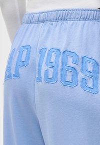 Φωτεινά γαλάζια φούτερ παντελόνια με ελαστική μέση, με ανάγλυφο κεντημένο κείμενο "GAP 1969" στην πίσω περιοχή του γοφού.