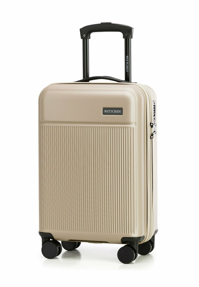 Beige tvrdý kufr s vertikálním rýhováním, černými koly a teleskopickou rukojetí. Na přední straně je umístěna nálepka s logem.