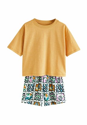 Kollane lühikeste varrukatega T-särk ümmarguse kaelusega, kombineeritud mustriliste lühikesed pükstega, millel on lilled ja abstraktne disain mitmesugustes värvides.