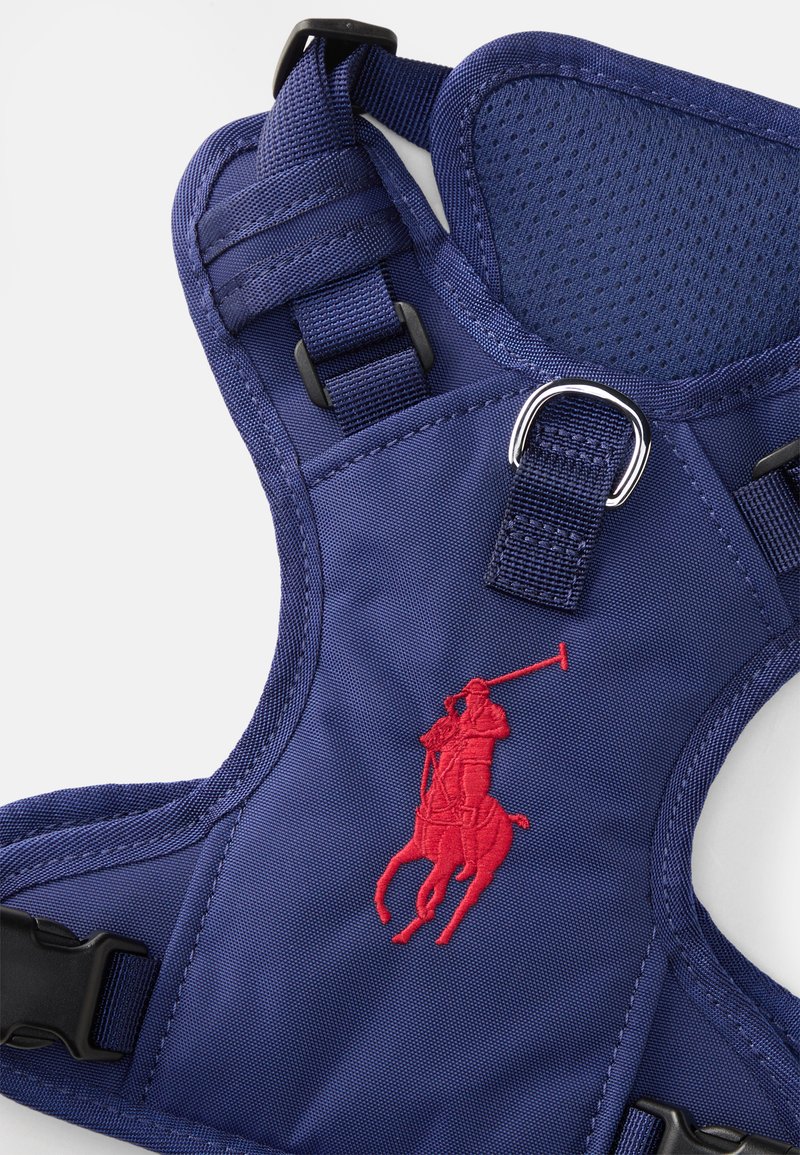 Marineblauwe hondentuig met een ademend gaasgedeelte, verstelbare banden en een rood geborduurd logo van een polo speler in een rijdende positie.