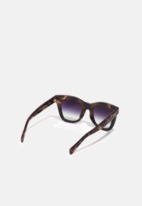 Gafas de sol de carey con un diseño geométrico. Lentes de degradado que van de un púrpura oscuro a tonos más claros, con brazos elegantes y detalle del logo.