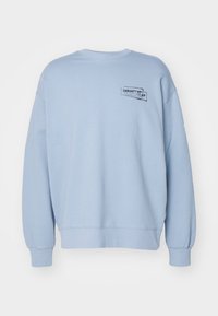 Sudadera de color azul claro hecha de un tejido suave, con cuello redondo y mangas largas. Logotipo negro impreso en la parte superior de la espalda.