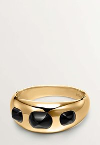 Brazalete de tono dorado que presenta tres piedras negras facetadas incrustadas en un diseño liso y redondeado. Textura brillante con un acabado sin costuras.