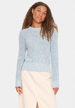 Light blue knitted sweater with a textured pattern, long sleeves, and a fitted waist. Paired with a cream-colored skirt.