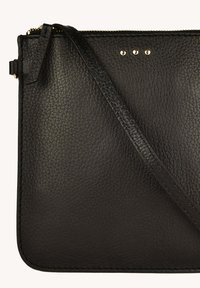 Sac en cuir noir à bandoulière avec une surface texturée, doté d'une fermeture à zip, d'une sangle réglable et de trois accents métalliques ronds.