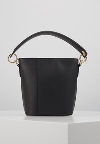 Sort læder bucket bag med en struktureret form, en kort hank, guldring hardware og en glat tekstur. Minimalistisk design uden yderligere accenter.