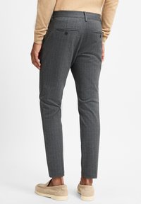 Grijze geruite broeken met een slim fit, gemaakt van een gestructureerde stof. Voorzien van twee achterzakken en gedragen met beige instappers.