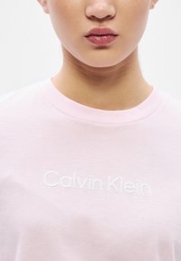 Ροζ βαμβακερό T-shirt με λευκό κεντημένο λογότυπο "Calvin Klein", στρογγυλή λαιμόκοψη και απαλή υφή.