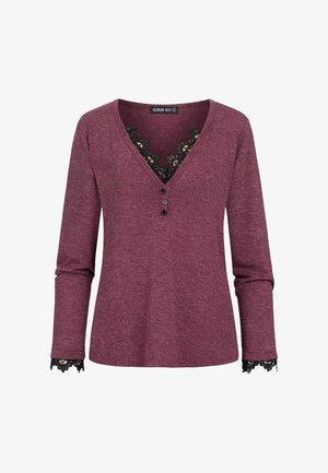 Bordeauxrode top met lange mouwen, een V-hals en zwarte kanten afwerking. Voorzien van drie knopen bij de halslijn en kanten details aan de manchetten.