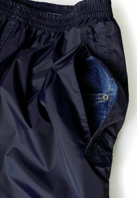 Marinblå simshorts i ett lätt, glänsande material, med en elastisk midja och en ficka fodrad med denim.