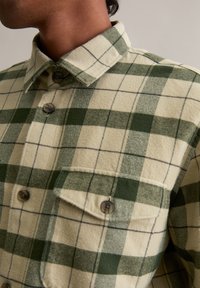 Groen-beige geruit flanellen overhemd met een button-down kraag, voorzien van twee borstzakken en een textuur in de stof met een zachte afwerking.