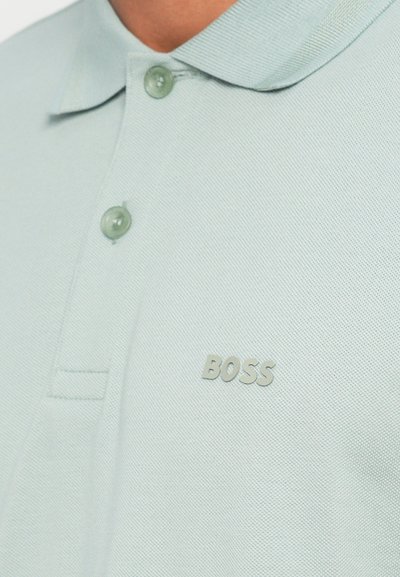 Polo vert clair en tissu texturé, doté d'un col classique, d'une fermeture à deux boutons et d'un logo "BOSS" en relief subtil.
