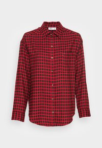 Camicia in flanella a quadri rossi e neri con maniche lunghe, tasca e abbottonatura frontale. Texture morbida e classico motivo a scacchi su tutta la superficie.