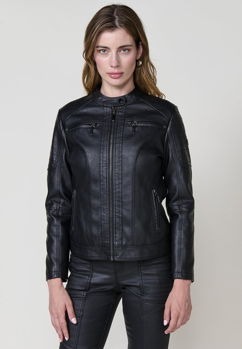 Čierna kožená motorkárska bunda s predným zipsom, vypchávkami na pleciach a dvoma prednými zipsovými vreckami. Obsahuje detail vertikálneho šitia.