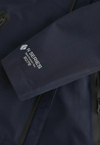Granatowa kurtka o matowej fakturze. Posiada zamek błyskawiczny, widoczne szwy oraz logo "N SERIES" nadrukowane na rękawie na biało.