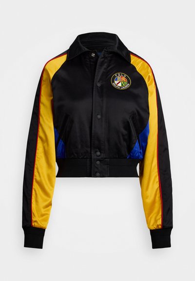 Σατέν τζάκετ κομμένο με μαύρο σώμα, κίτρινες και μπλε πλευρές, ριμπ τελείωμα, κεντημένο λογότυπο στο στήθος, κούμπωμα με κουμπιά και αντίθετες ρίγες.
