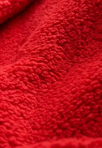Roter strukturierten Fleece-Stoff mit einer weichen, flauschigen Oberfläche, der ein wellenförmiges Muster und eine satte, einheitliche Farbe aufweist.
