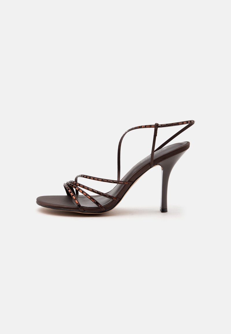 Sandale marron à talons hauts avec des fines lanières à motifs et un talon aiguille fin sur fond blanc.