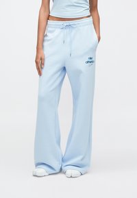 Világoskék elasztikus derékpántú és húzózsinóros melegítőnadrág, bal combján kék Nike logóval, puha pamut anyagból készült.